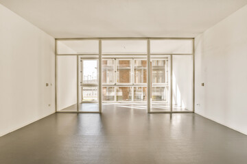 an empty room with white walls and large glass doors that open to the outside, looking out onto the street