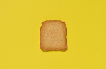 One slice of white wheat toast on a yellow background, top view