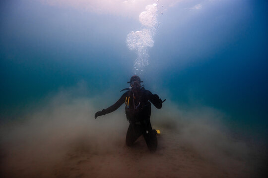 Anonymous person in diving mask fins swimming underwater