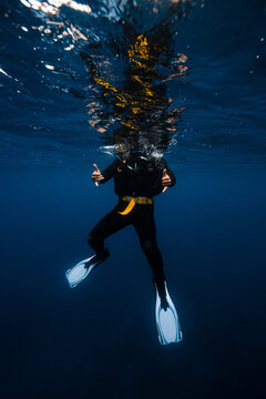 Anonymous person with thumps up diving in seawater