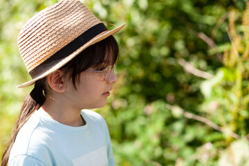 Portrait of a girl in a straw hat against the background of nature