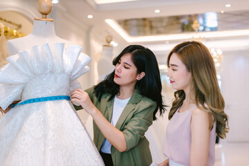 Naklejka premium Female bridal store owner work in wedding studio shop. Owner Of Bridal Wedding Dress Shop Work in shop. Designer woman working wedding dress in store..