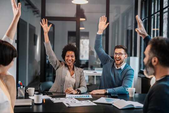 A multicultural group of businesspeople is voting for ideas for project.