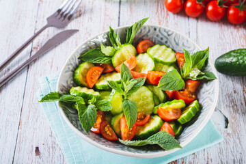Diet salad of cucumbers, tomatoes and mint in a bowl on the table