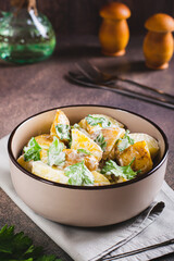 Potato salad in a peel with parsley and mayonnaise in a bowl on the table vertical view