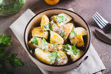 Delicious potato salad with parsley and mayonnaise in a plate on the table