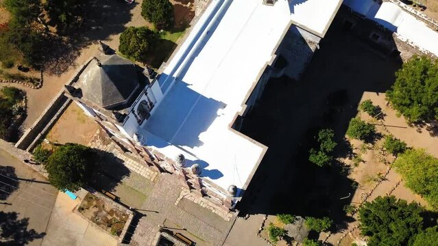 Aerial Shot Of Catholic Church Amidst Plants On Sunny Day, Drone Descending Over Mission San Ignacio Kadakaaman - Baja California, Mexico