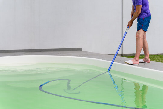 Man cleaning bottom of private pool with vacuum cleaner