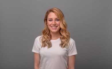 Fototapeta premium Smiling girl on a grey background, crossed her arms over her chest.