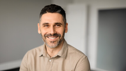 Happy successful european middle aged male entrepreneur looking aside and smiling, office interior, panorama, free space