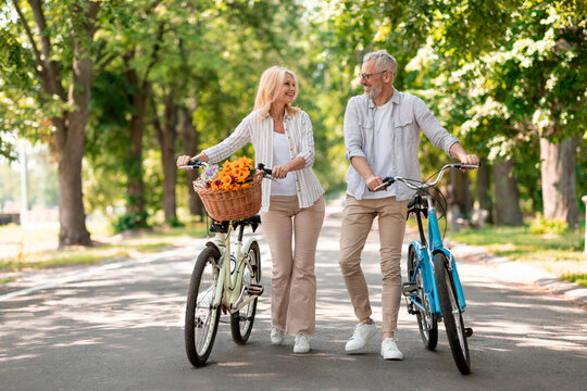 Happy Senior Couple With Retro Bikes Walking Together In Summer Park