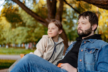 Fototapeta premium Caucasian bearded man with his little son in park on autumn day. Image with selective focus