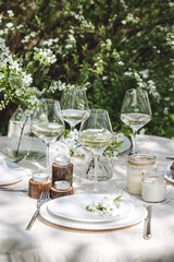 Romantic elegant luxury wedding table decor with white fresh spring blooming cherry apple tree flowers. Glass, candles, floral decoration for special marriage holiday event. No plastic zero waste