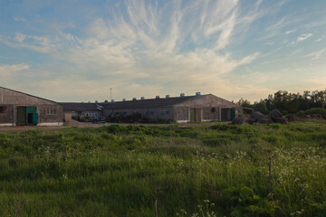 Obraz premium A field and hay bales in front of an old dairy farms against the blue sky on a warm summer day