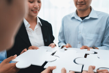 Diverse corporate officer workers collaborate in office, connecting puzzle pieces to represent...