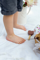 A child's foot near a picnic basket on a white blanket