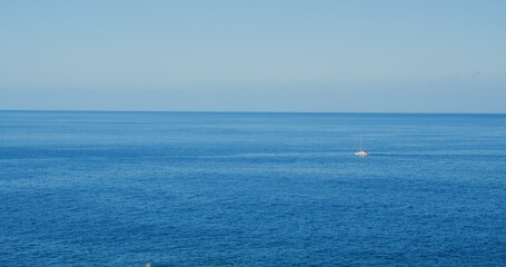 Fototapeta premium Sailing yacht race at sun light aerial. Yachting on serene seascape at open sea. Boat with big white spinnaker sail at ocean bay. Lonely ship cruise at water on summer sunny day. Cinematic drone shot