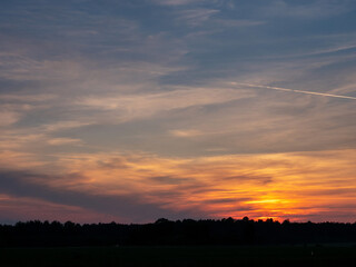 Stunning colorful sunset sky over a forest silhouette. Warm and cool color. Beautiful nature scene. Calm and relaxing mood and atmosphere. Nobody.
