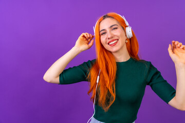 Redhead woman in studio photography smiling dancing on a purple background