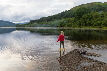 Fototapeta na wymiar Child playing on a Loch in the Scottish Highlands, on a summers day