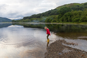 Fototapeta na wymiar Child playing on a Loch in the Scottish Highlands, on a summers day