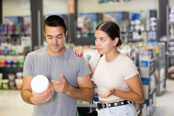 Fototapeta na wymiar Married couple choosing a can of paint together in a hardware store
