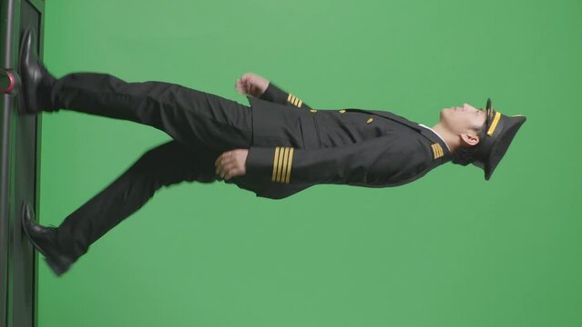 Full Body Of Asian Man Pilot Holding A Tablet While Walking On Treadmill In The Green Screen Background Studio
