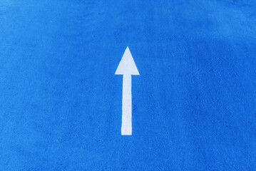 A white direction sign on a blue painted floor