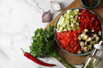 Cooking delicious ratatouille. Fresh ripe vegetables and plate on white marble table, flat lay....