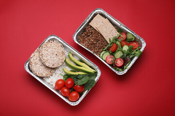 Containers with different fresh food on red background, flat lay