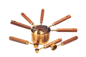Copper measuring cups/spoons with wooden handle in sets of different sizes on white background.
