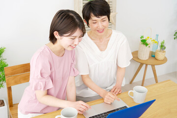 Obraz na płótnie Canvas 自宅でノートパソコンを使う母親と娘