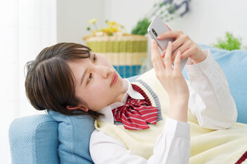 自宅でスマートフォンを使う女子高生