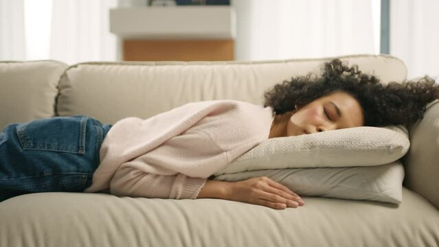 Exhausted tired lazy young african american woman falls down on sofa. Apathetic bored lady sleeping on couch at home alone. Funny girl lying asleep feeling out of energy motivation, depression concept
