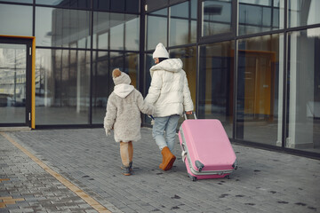 Mother and daughter with luggage going to airport terminal
