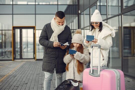 Family standing outdoors with luggage and checking passports
