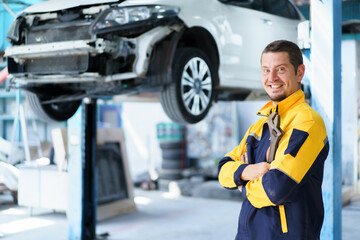 Professional caucasian white automobile technician holding a wrench and making crossed arms and looking at camera.
