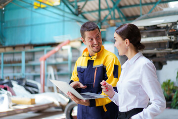 Caucasian white young woman taking her car to garage to have an annual check up and talking or discussing to technician. Automobile repairing and diagnostics service business concept.
