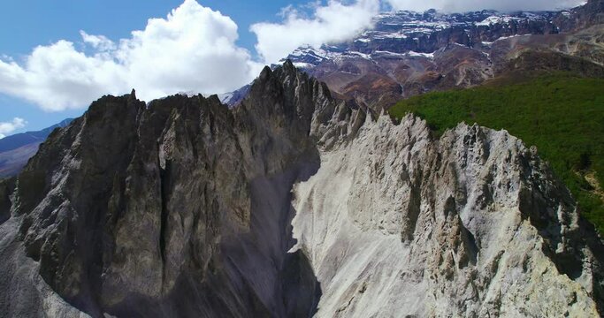 Drone shot of Mountain peaks of muddy mountain at Manang Nepal surrounded by Landscapes and hills under cloudy blue sky. Peace and calm 4k.