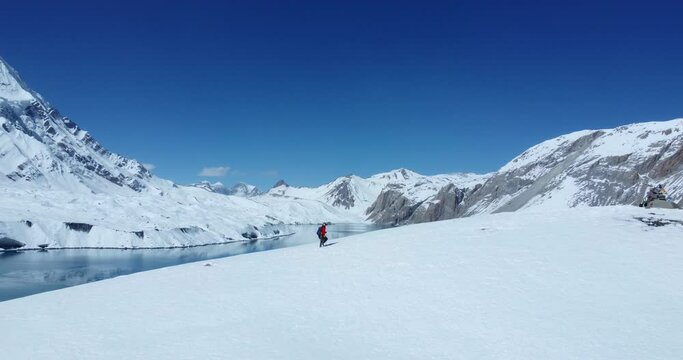 Drone shot of the World's largest Lake Tilicho in Manang Nepal. A man returns after enjoying the view of Lake reflecting Mountain in it. Peaceful adventurous trek Moment and lifetime experience. 4K