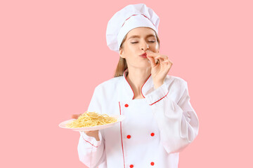 Female chef with tasty pasta on pink background