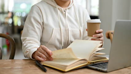 Cropped image of a woman sipping coffee while remote working at a coffee shop