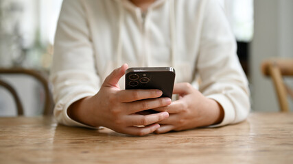 Cropped image of a woman using her smartphone at a table while relaxing in the coffee shop.