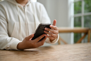 A woman chatting with her friends through her smartphone while sitting at a table in the cafe.