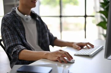 Close-up image of a male programmer in a flannel shirt using his computer in the office.