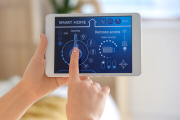 Young woman using smart home security system control panel in bedroom, closeup