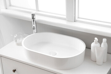 White sink with bath accessories on chest of drawers, closeup