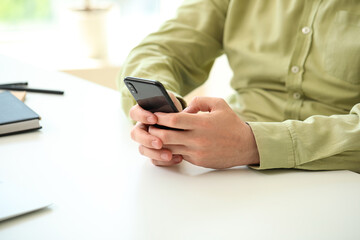 Man with smartphone at table, closeup