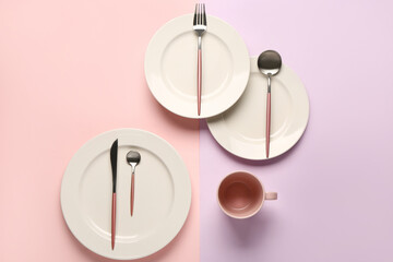 Clean plates, cutlery and cup on colorful background