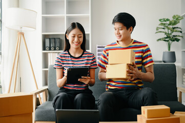 Naklejka premium Starting small businesses SME owners, two check online orders Selling products working with boxs freelance work on sofa at home using tablet and laptop marketing, packaging, concept.